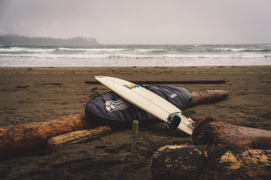 A surfboard leaning on a log on the beach
