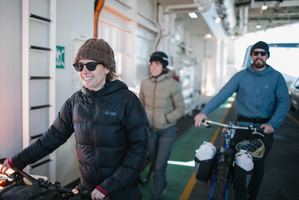 Three people walking bicycles on a ferry