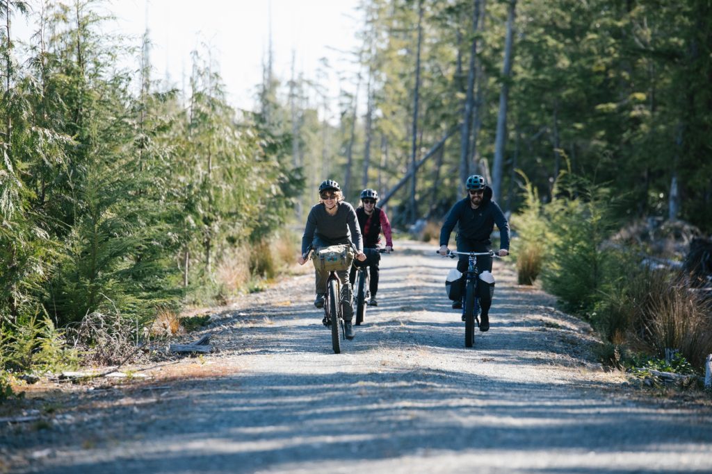 Three cyclists on a gravel road surrounded by forest