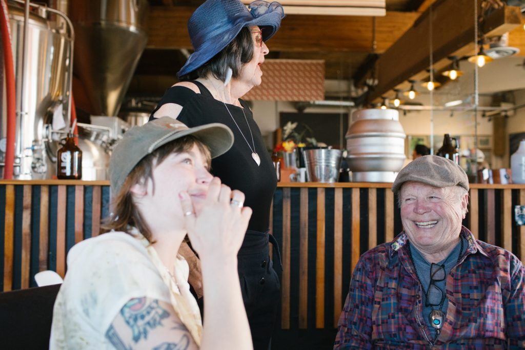 Two people at a brewery laughing with a server