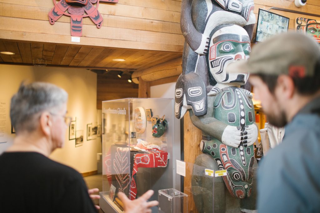 A person showing another person a First Nation's art piece